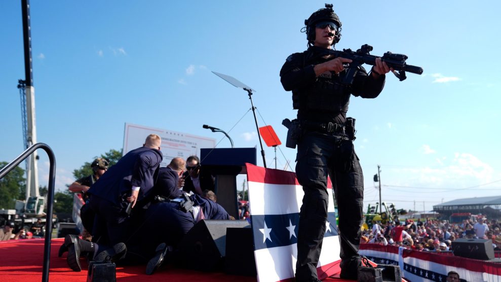 A countersniper stands on the stage at the site of the first assassination attempt of Trump in Butler, Pennsylvania, while several Secret Service Agents crouch on the stage to protect the president.